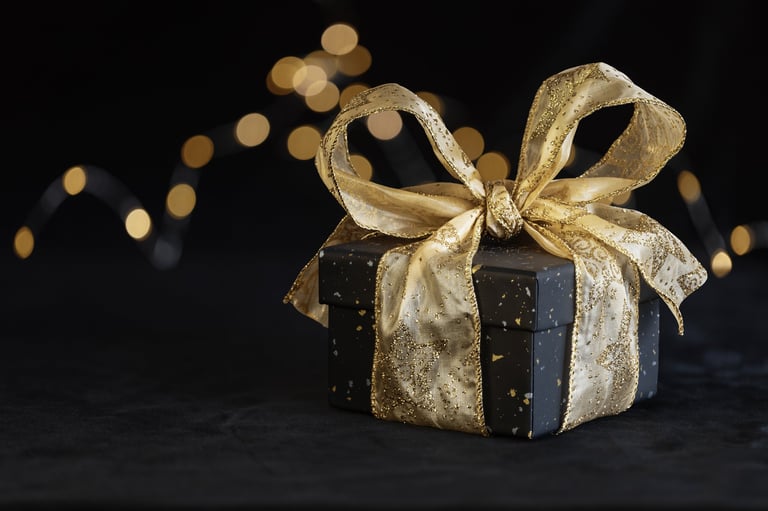 Black gift box with golden ribbon bow on black plush background