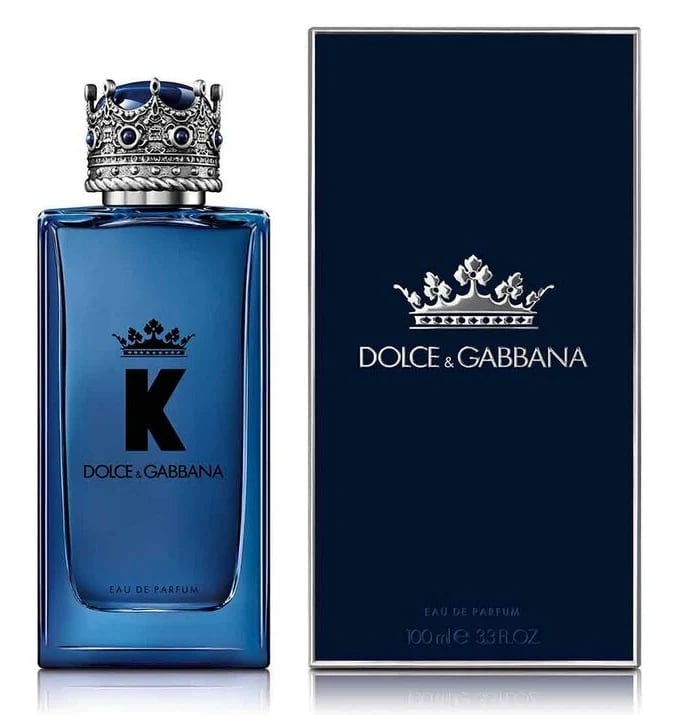 Dolce and Gabbana K eau de parfum bottle with ornate crown stopper next to its dark navy packaging box