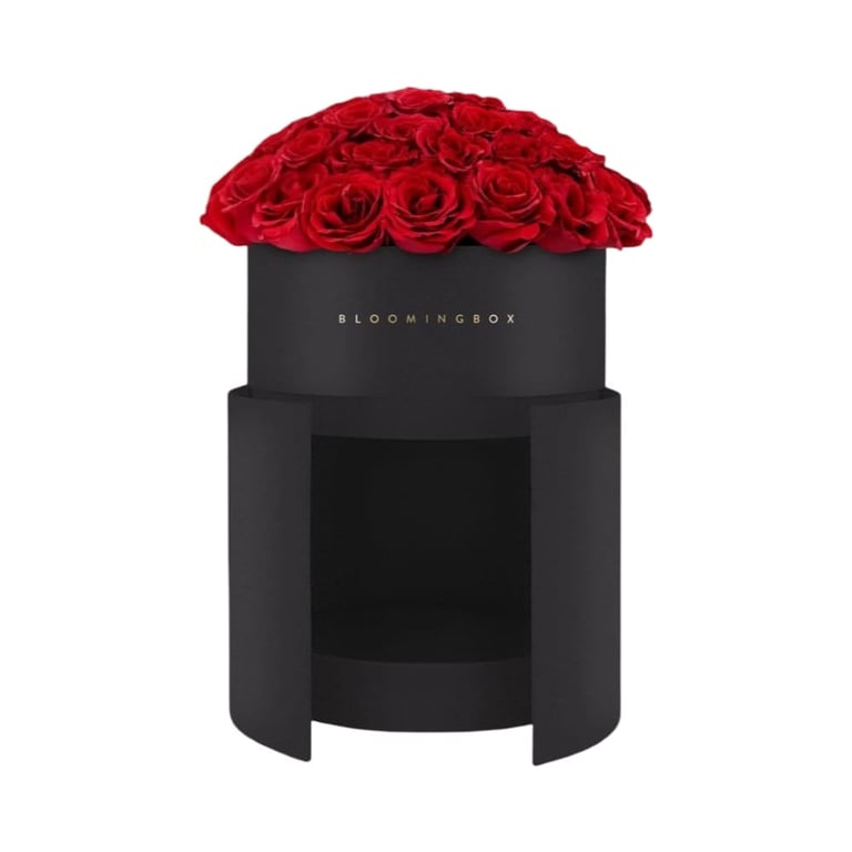 Black cylindrical luxury floral box with red roses arranged on top by BloomingBox